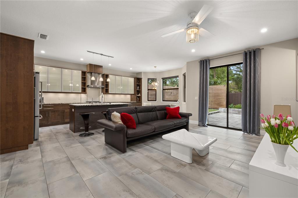 An open-concept kitchen and living area features dark cabinetry, a kitchen island, and tile flooring — 3526 E CRYSTAL LAKE AVENUE, ORLANDO, FL