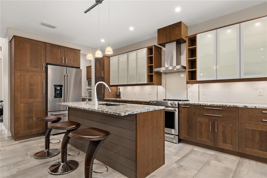A modern kitchen features wood cabinets, granite countertops, a central island, and stainless steel appliances — 3526 E CRYSTAL LAKE AVENUE, ORLANDO, FL
