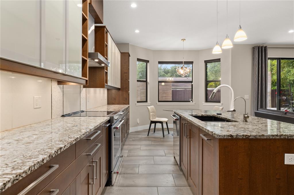 A modern kitchen features wood cabinets, granite countertops, a center island, and a dining nook — 3526 E CRYSTAL LAKE AVENUE, ORLANDO, FL