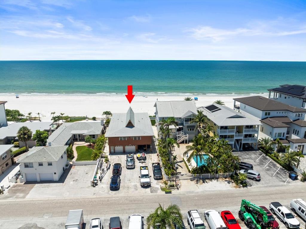 An aerial view shows a beachfront house with a red arrow pointing to its roof — 18218 SUNSET BOULEVARD UNIT A, ST PETERSBURG, FL