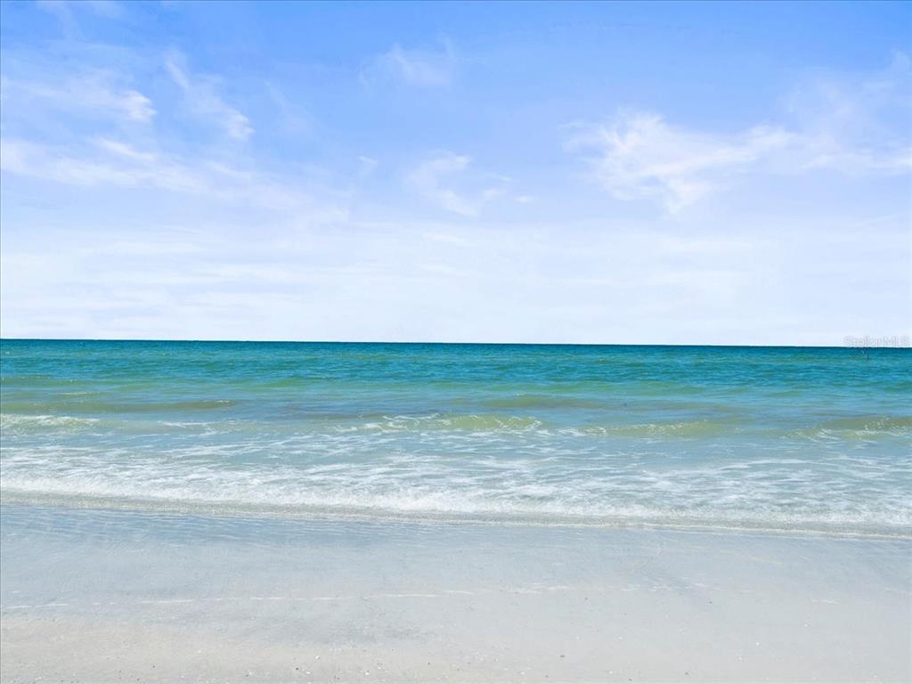 A view of a sandy beach meeting the turquoise ocean under a blue sky — 18218 SUNSET BOULEVARD UNIT A, ST PETERSBURG, FL