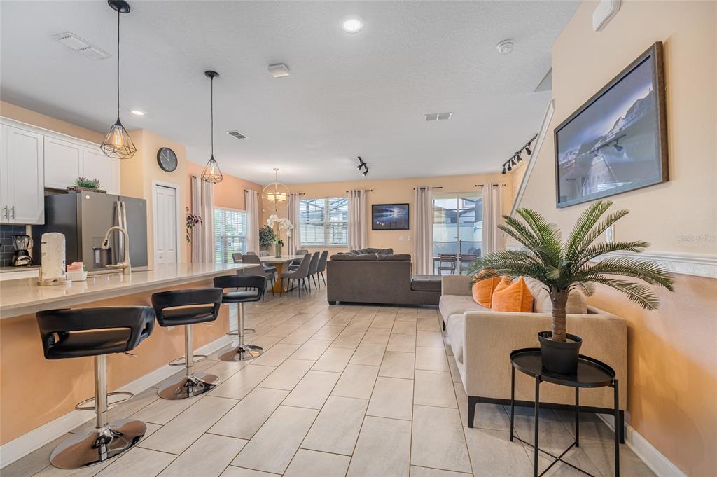 An open-concept living area features a kitchen with bar seating, a dining space, and furniture — 4800 MEMORIES LANE, KISSIMMEE, FL