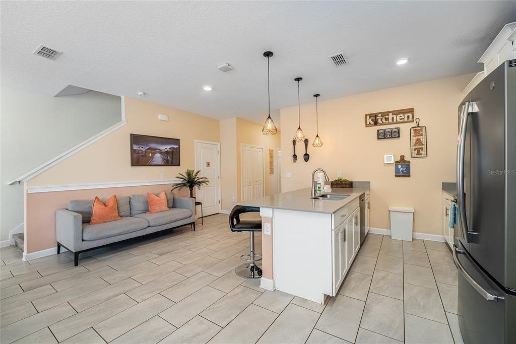 A kitchen with a center island and breakfast bar next to a living area — 4800 MEMORIES LANE, KISSIMMEE, FL