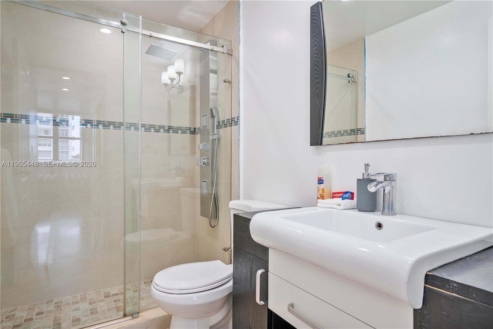 A bathroom features a glass-enclosed shower, a white vanity, and a toilet — 5601 Collins Ave # 423, Miami Beach FL 33140, MIAMI BEACH, FL