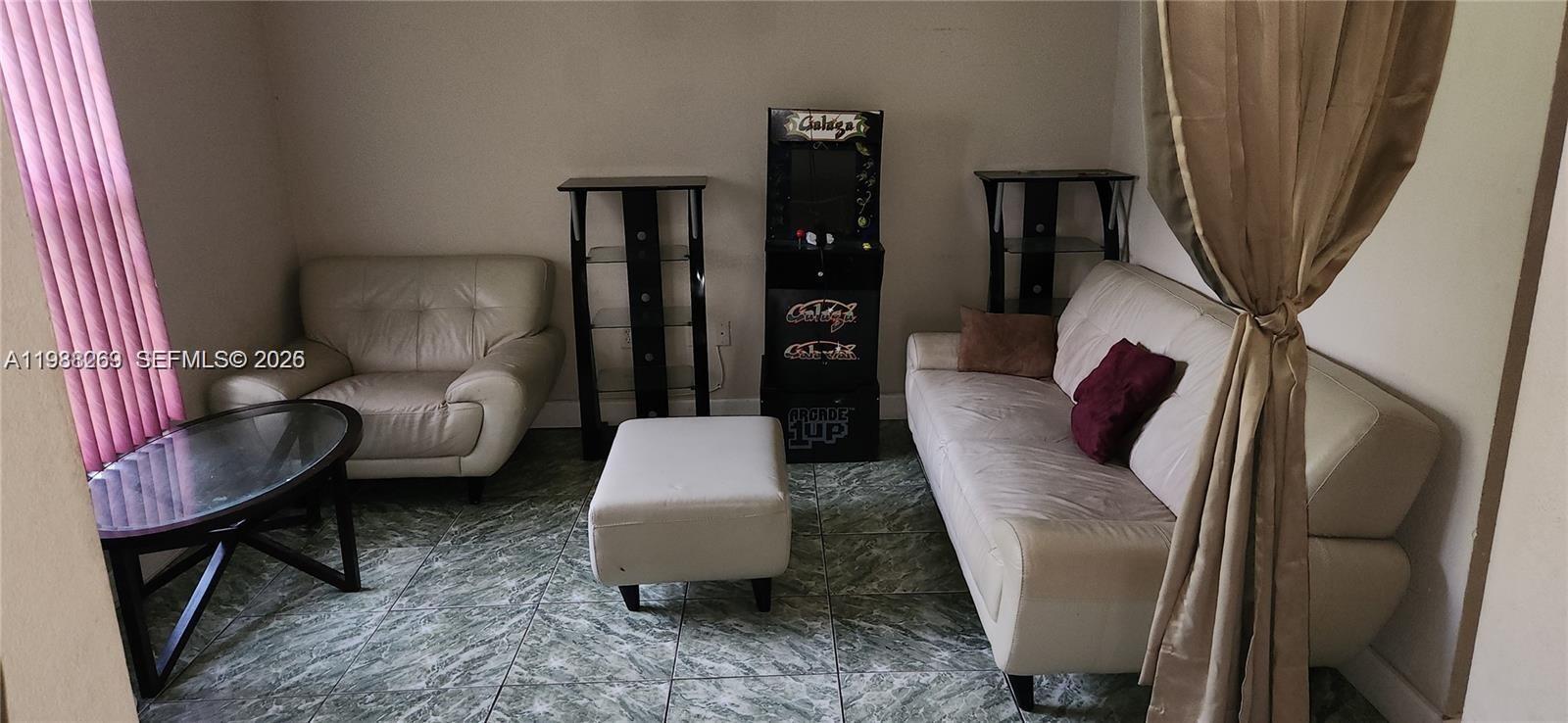 A living room features a white sofa, a matching armchair, an ottoman, and an arcade cabinet — 18963 SW 113th Ct, Miami FL 33157, MIAMI, FL