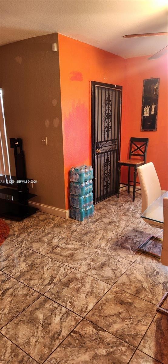 A dining area features orange walls, tiled flooring, a metal security door, and a chair — 18963 SW 113th Ct, Miami FL 33157, MIAMI, FL