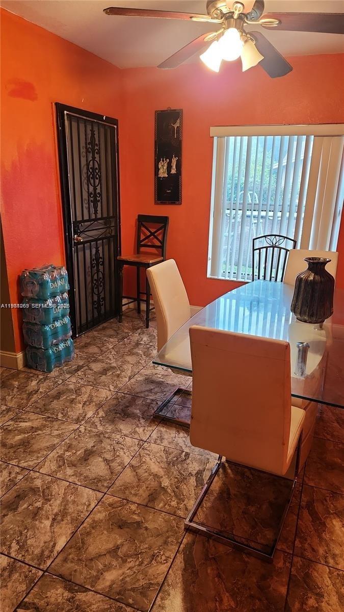 A dining room features orange walls, tile flooring, a glass table, and a ceiling fan — 18963 SW 113th Ct, Miami FL 33157, MIAMI, FL