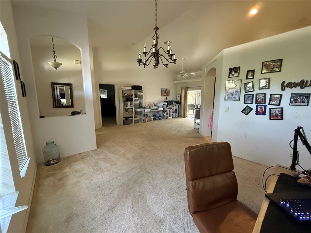 A carpeted living area features a chandelier, a gallery wall, and an adjacent office space — 4619 ITALY AVENUE, NORTH PORT, FL