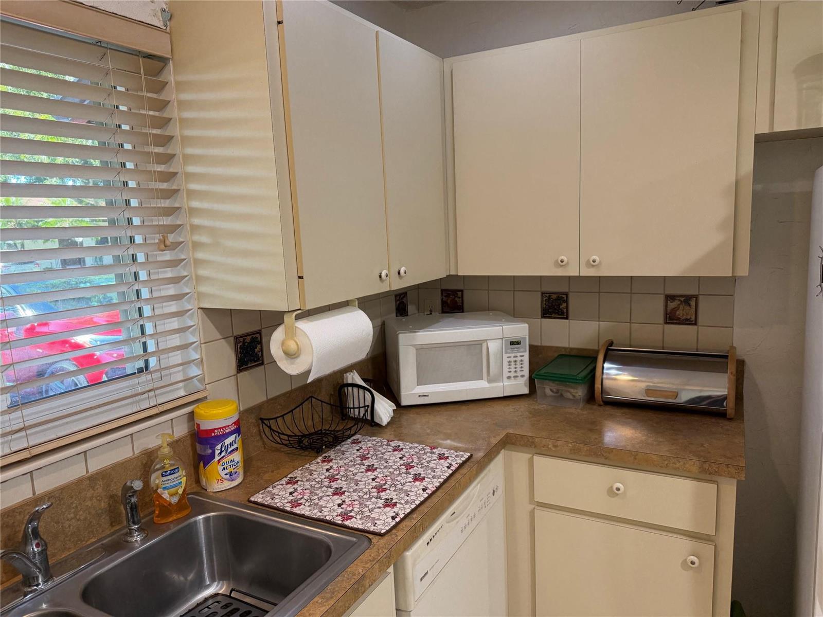 A kitchen features off-white cabinets, a stainless steel sink, a microwave, and tan countertops — 6711 S Parkway Drive # 10, Margate FL 33068, MARGATE, FL