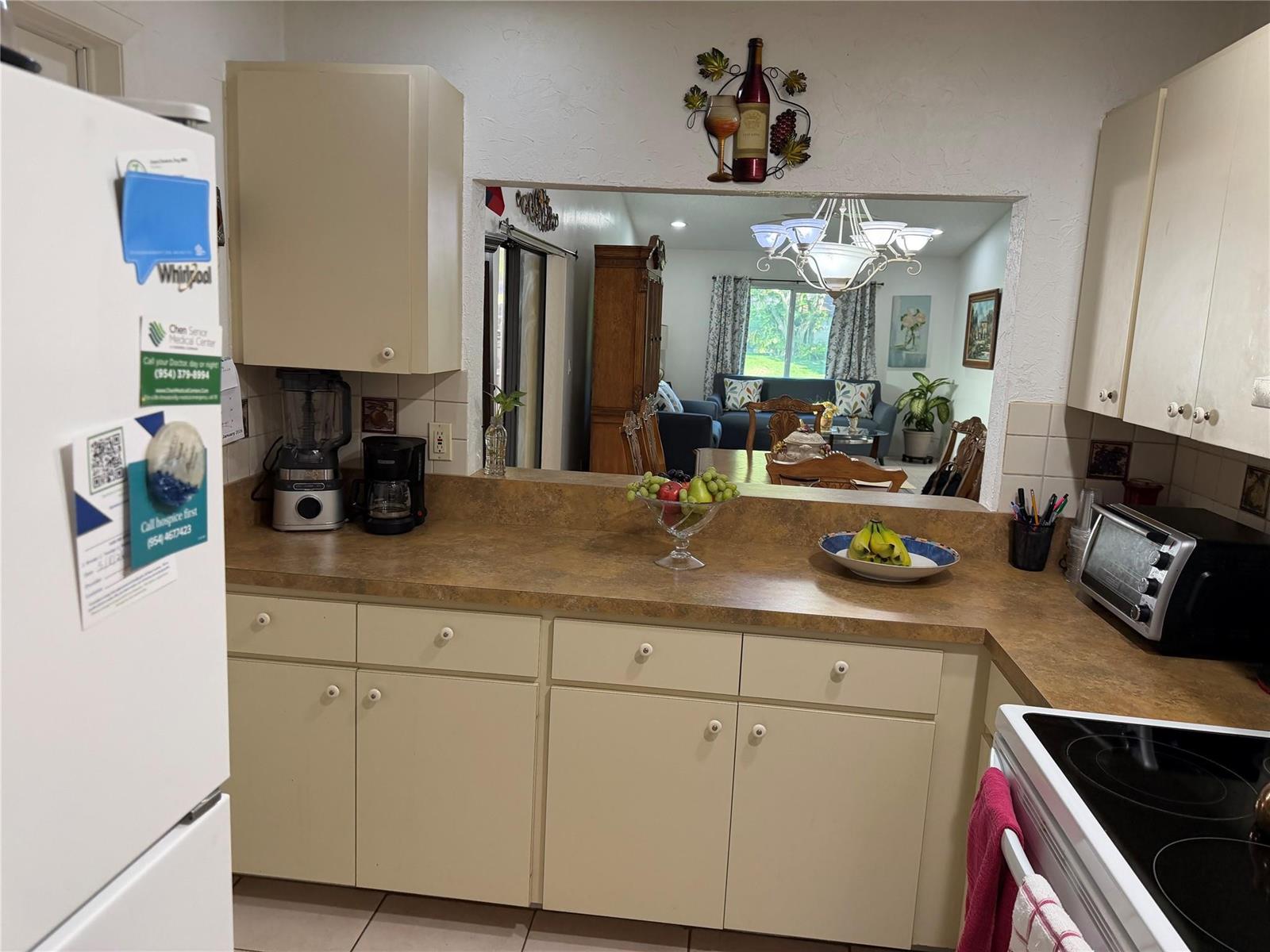A kitchen with beige cabinets, laminate countertops, and a pass-through window looking into the living room — 6711 S Parkway Drive # 10, Margate FL 33068, MARGATE, FL