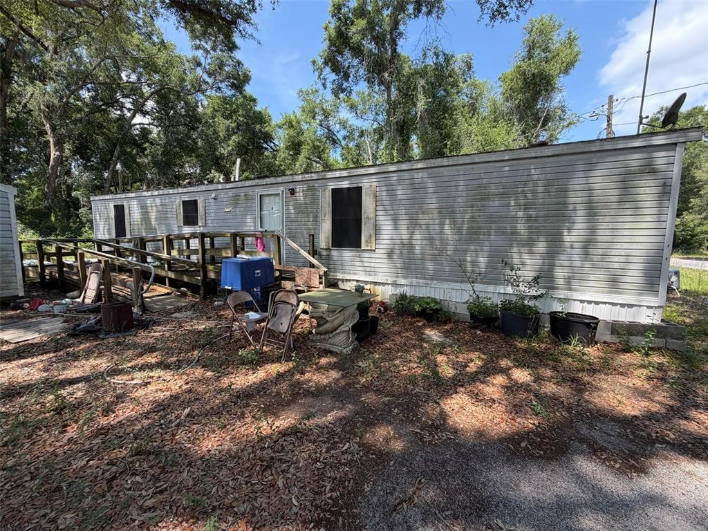 A single-wide mobile home with a wooden wheelchair ramp and outdoor seating area — 369 CR 552N, BUSHNELL, FL