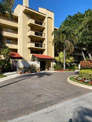 A multi-story tan apartment building with balconies and a brick driveway entrance — 825 Egret Circle # 404, Delray Beach FL 33444, DELRAY BEACH, FL