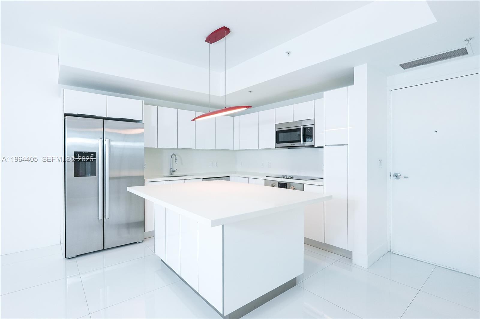 A modern kitchen features white cabinetry, stainless steel appliances, and a large central island — 1010 SW 2nd Ave # 606, Miami FL 33130, MIAMI, FL