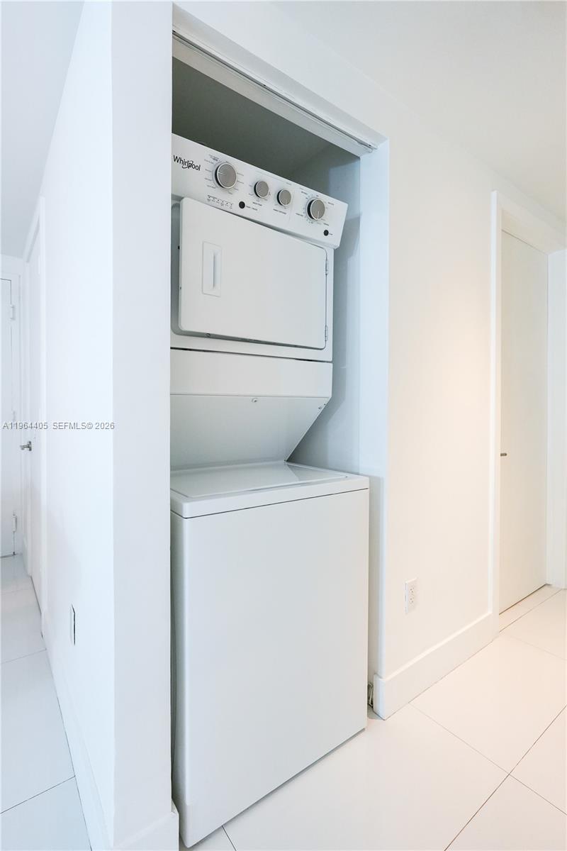A white stacked Whirlpool washer and dryer unit is installed in a small wall alcove — 1010 SW 2nd Ave # 606, Miami FL 33130, MIAMI, FL