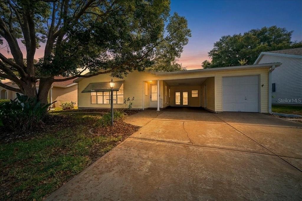 A screened-in patio features a brick paver floor, two white rocking chairs, and lattice trim — 1133 DEL TORO DRIVE, LADY LAKE, FL