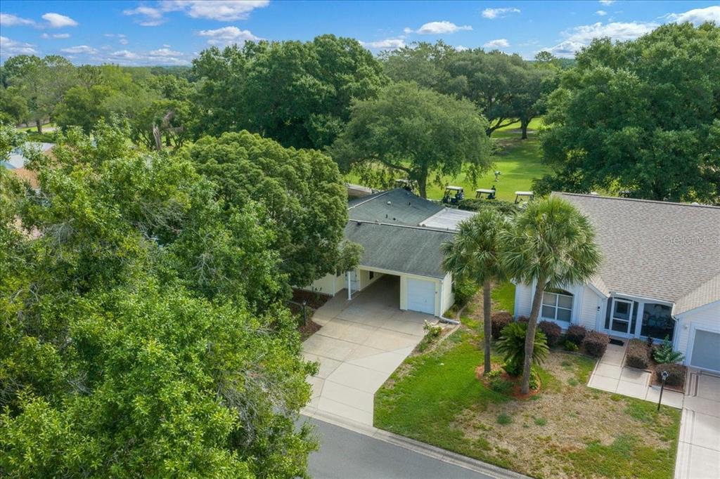 An aerial view shows a golf course green and fairway adjacent to a residential neighborhood — 1133 DEL TORO DRIVE, LADY LAKE, FL