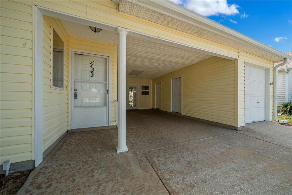 An aerial view shows a house with a carport and driveway next to a golf course — 1133 DEL TORO DRIVE, LADY LAKE, FL
