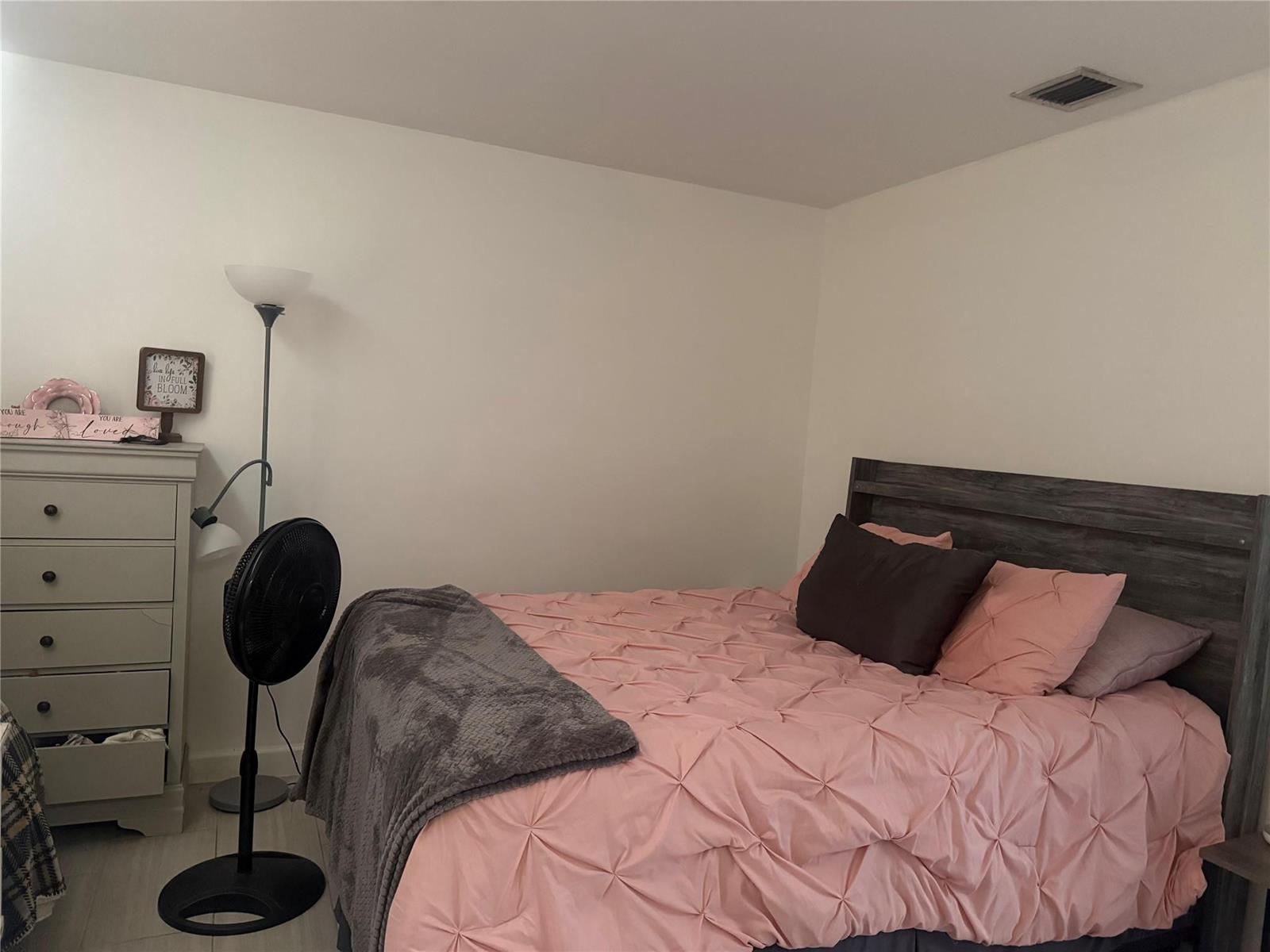 A bedroom features a bed with pink bedding, a gray headboard, and a tall dresser — 817 SE 9th Street, Okeechobee FL 34974, OKEECHOBEE, FL