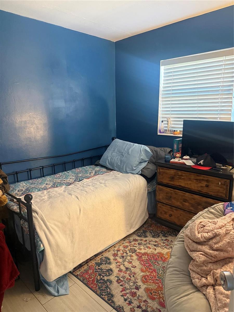 A bedroom features a metal daybed, a wooden dresser, and a colorful patterned area rug — 817 SE 9th Street, Okeechobee FL 34974, OKEECHOBEE, FL