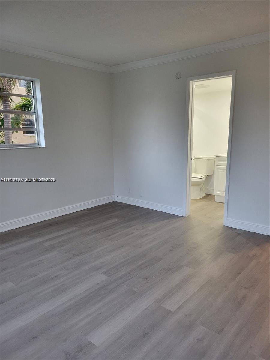 An empty room with light gray walls, wood-look flooring, a window, and an attached bathroom — 1333 E Hallandale Beach Blvd # 329, Hallandale Beach FL 33009, HALLANDALE BEACH, FL