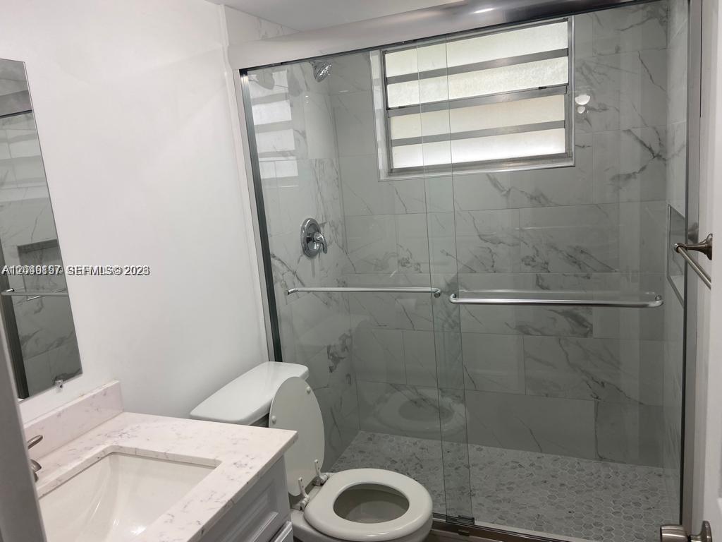 A bathroom features a marble-tiled walk-in shower with a glass door and a vanity — 1333 E Hallandale Beach Blvd # 329, Hallandale Beach FL 33009, HALLANDALE BEACH, FL