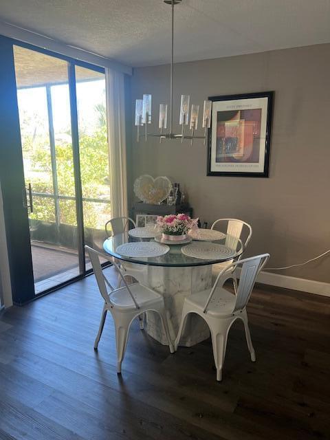 A dining area features a glass-topped table, four white metal chairs, and a modern chandelier — 955 Dotterel Road # 2111, Delray Beach FL 33444, DELRAY BEACH, FL