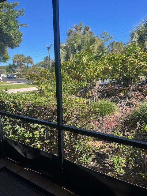A view of a landscaped yard and parking area seen through a screened-in porch — 955 Dotterel Road # 2111, Delray Beach FL 33444, DELRAY BEACH, FL