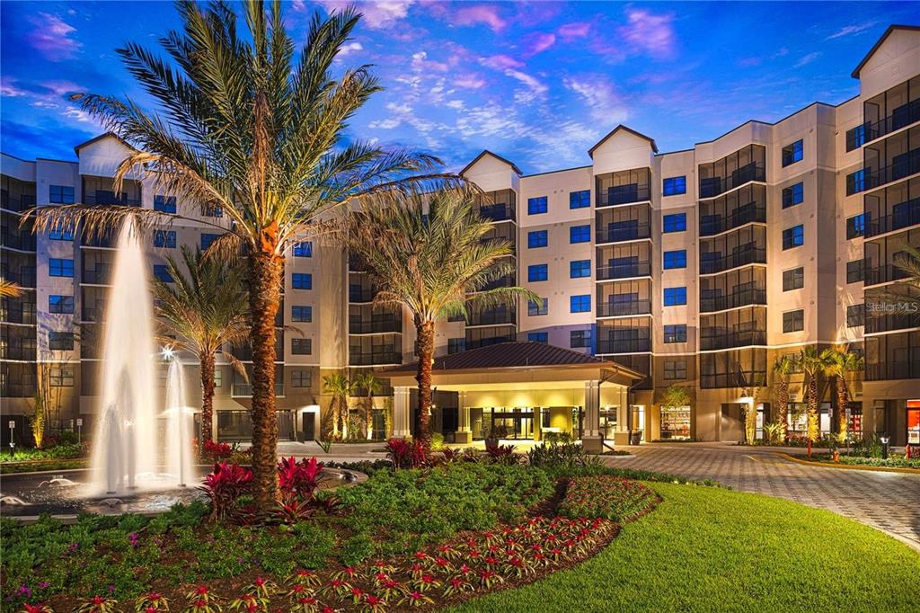 A multi-story apartment building exterior features a large fountain and a covered entrance at dusk — 14501 GROVE RESORT AVENUE UNIT 1439, WINTER GARDEN, FL