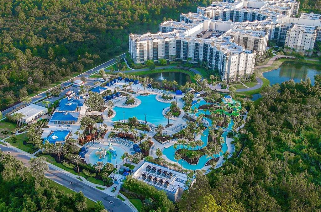 An aerial view of a resort complex featuring large swimming pools, waterslides, and surrounding woods — 14501 GROVE RESORT AVENUE UNIT 1439, WINTER GARDEN, FL