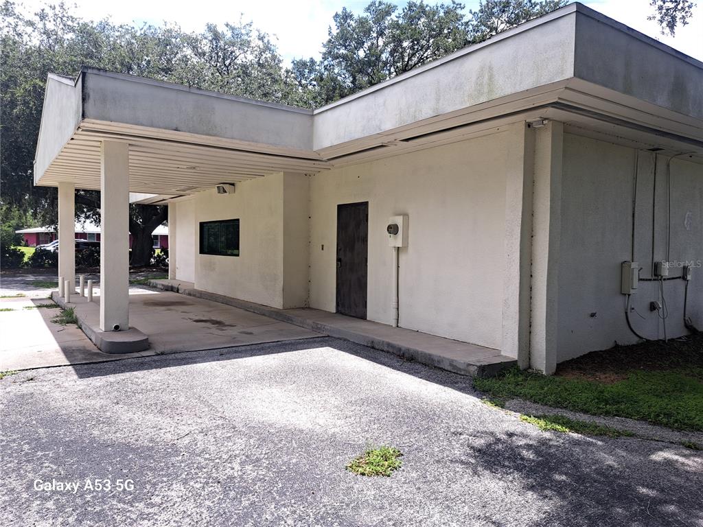 An exterior view of a white commercial building with a covered drive-through area — 6481 DELAND AVENUE, INDIAN LAKE ESTATES, FL