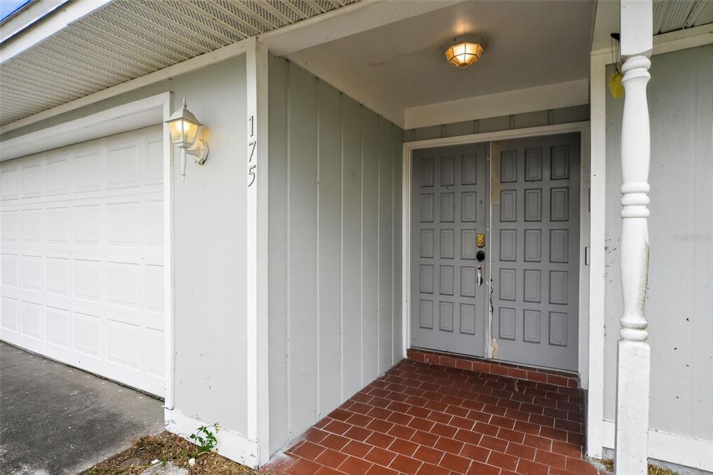 The exterior entrance features a double door, a brick porch, and a garage door — 175 SHERIDAN AVENUE, LONGWOOD, FL
