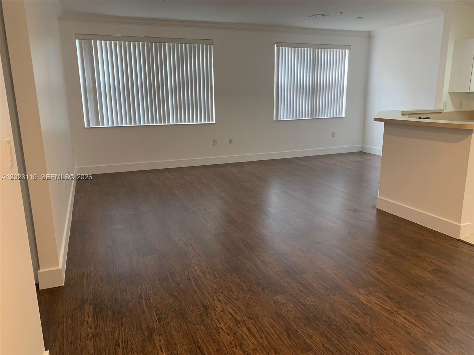 An empty room features dark wood-look flooring, white walls, and two windows with vertical blinds — 4702 SW 160th Ave # 325, Miramar FL 33027, MIRAMAR, FL