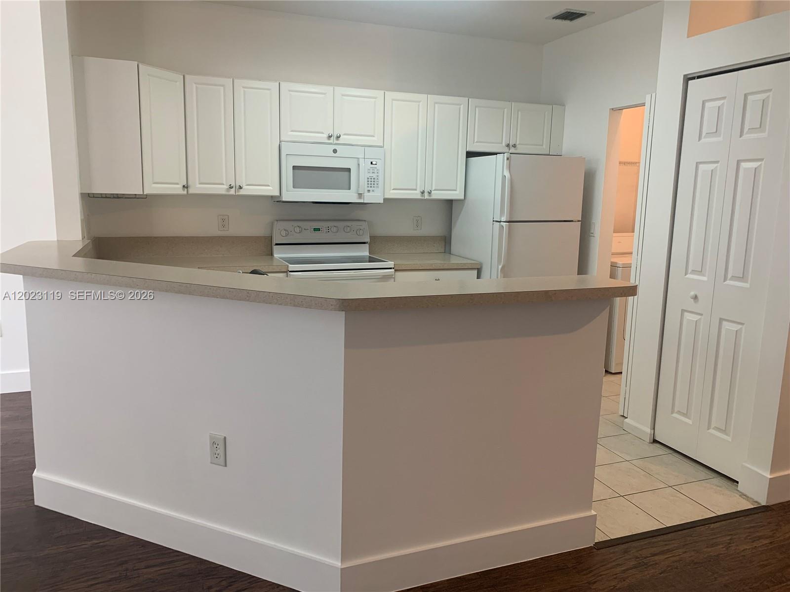 A kitchen features white cabinets, white appliances, and a peninsula counter with a beige top — 4702 SW 160th Ave # 325, Miramar FL 33027, MIRAMAR, FL