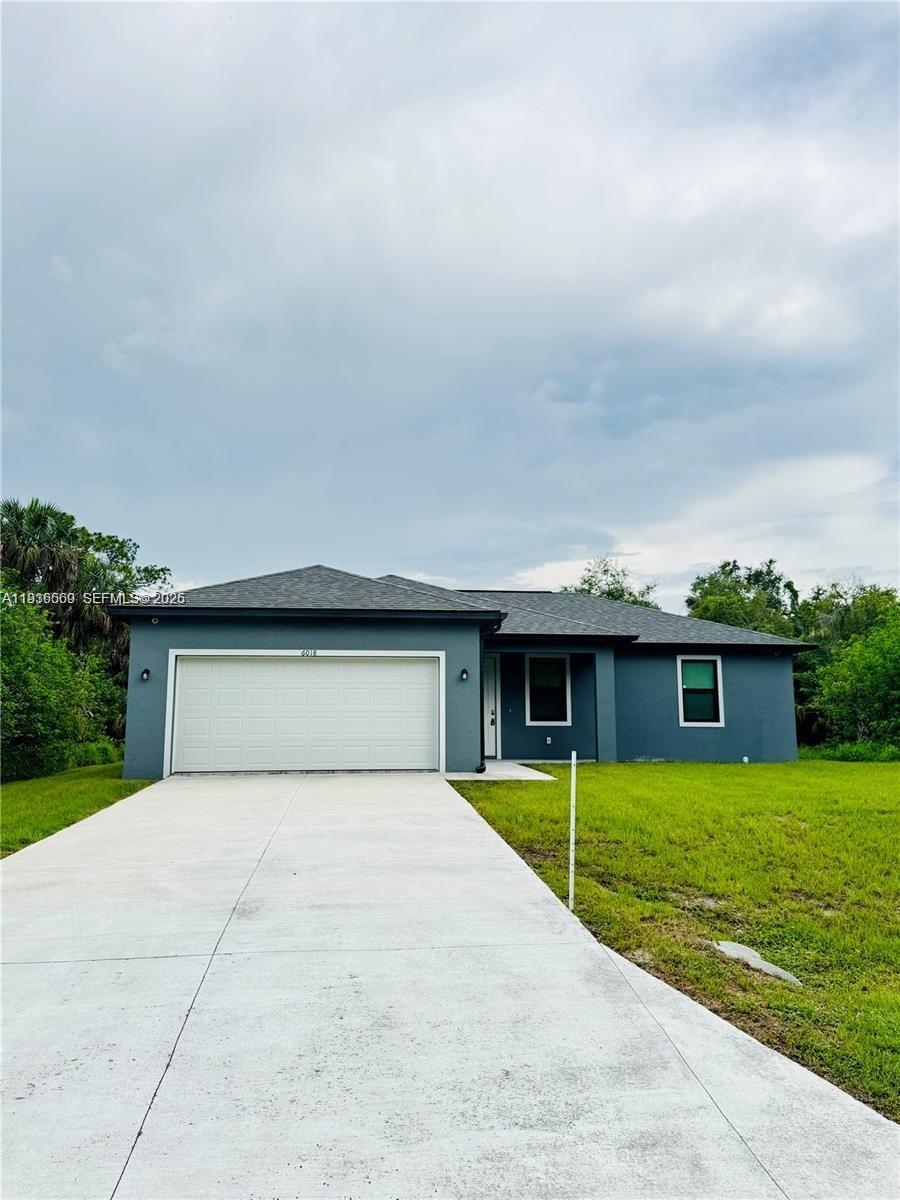 A single-story house with a gray exterior, a two-car garage, and a concrete driveway — 6018 ACORN CIR, La Belle FL 33935, LA BELLE, FL