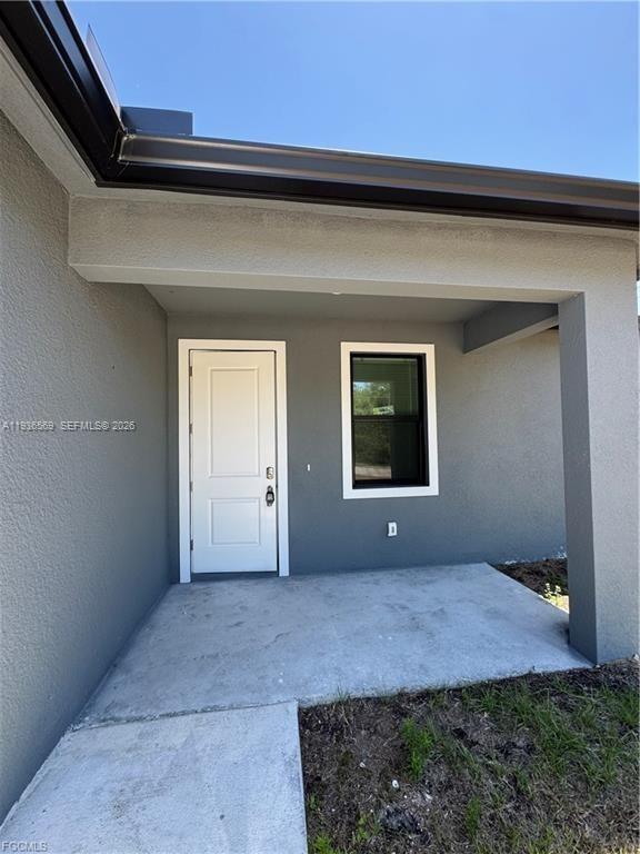 A covered concrete entryway features a white door and a single window on gray walls — 6018 ACORN CIR, La Belle FL 33935, LA BELLE, FL