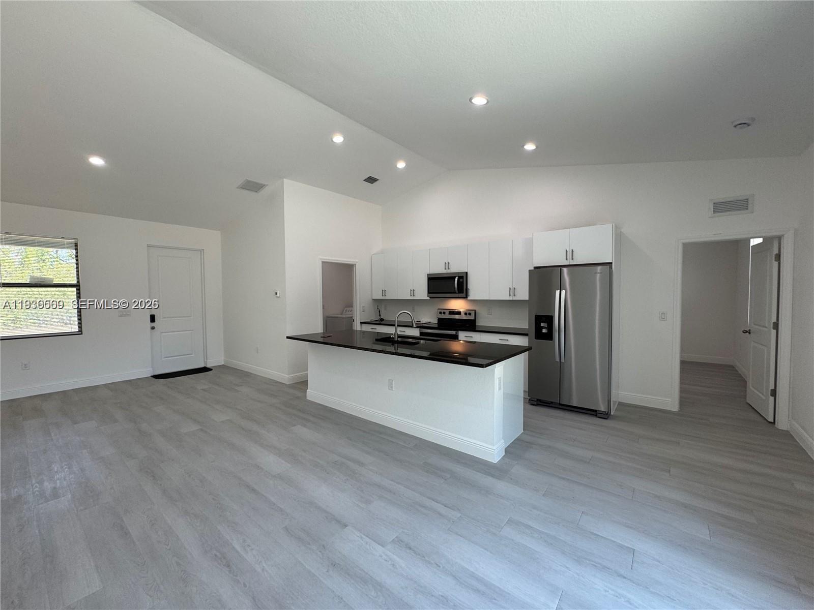 A modern kitchen features white cabinets, stainless steel appliances, and a black island countertop — 6018 ACORN CIR, La Belle FL 33935, LA BELLE, FL