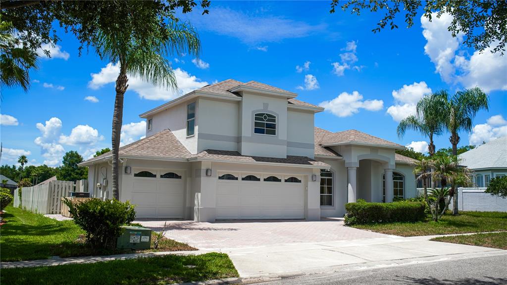 A two-story house with a three-car garage, beige stucco exterior, and a paved driveway — 3851 HUNTERS ISLE DRIVE, ORLANDO, FL
