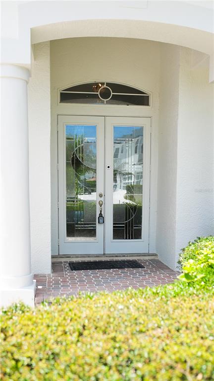 A white double front door with glass panels and a transom window under an archway — 3851 HUNTERS ISLE DRIVE, ORLANDO, FL