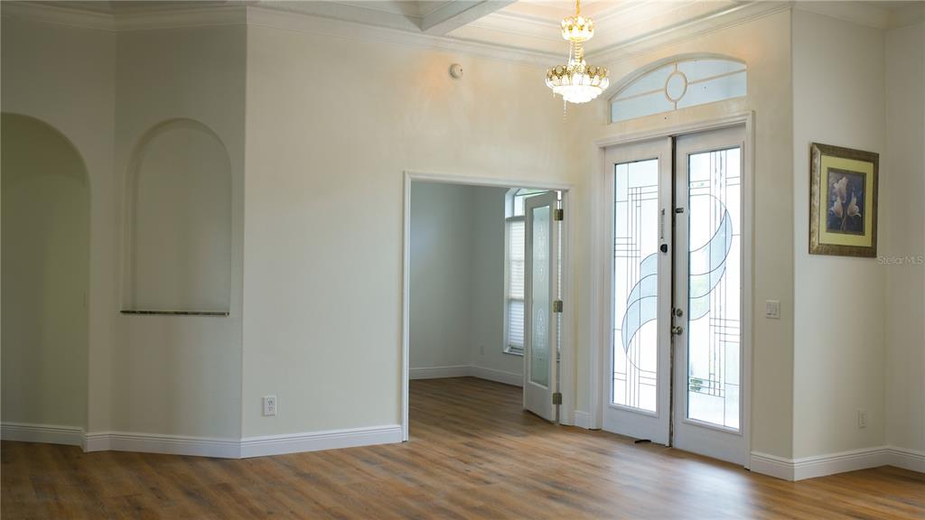 An entryway features wood-look flooring, a glass-paneled double door, and a decorative chandelier — 3851 HUNTERS ISLE DRIVE, ORLANDO, FL