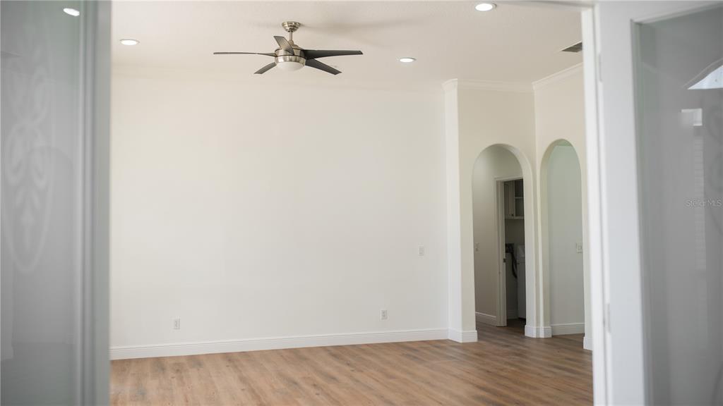 A room with light-colored walls, wood-look flooring, a ceiling fan, and arched doorways — 3851 HUNTERS ISLE DRIVE, ORLANDO, FL