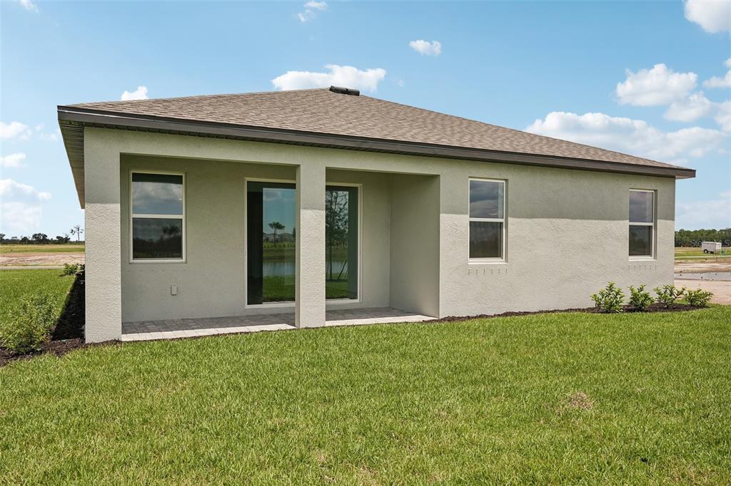 The exterior rear view of a single-story house features a covered patio and lawn — 13814 BERTRAND AVENUE, PALMETTO, FL