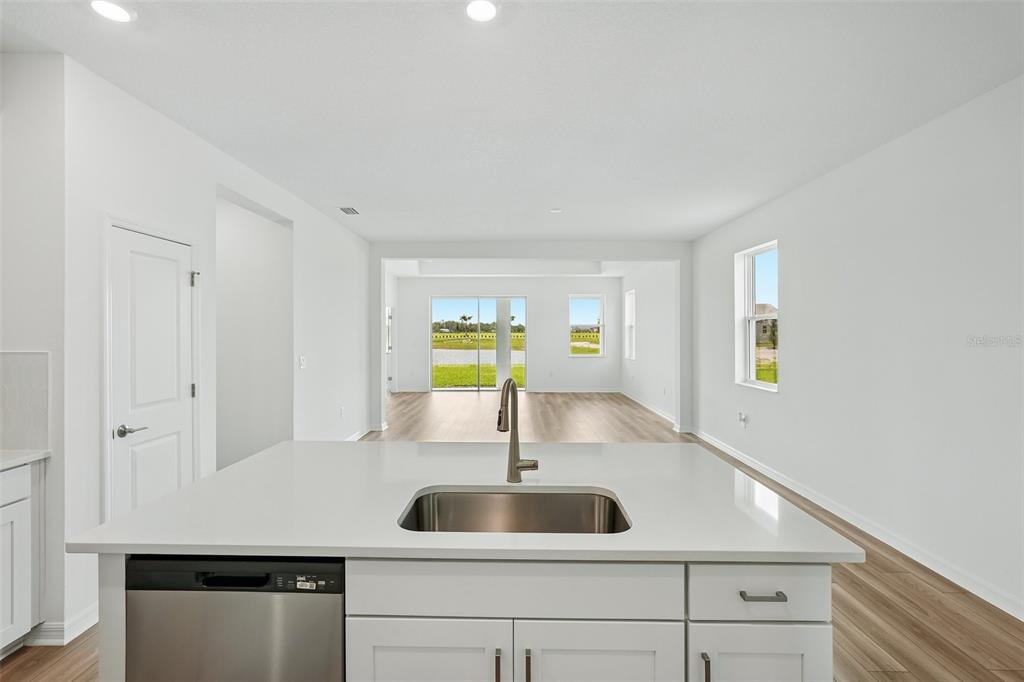 A kitchen island with a stainless steel sink faces an open-concept living area with sliding doors — 13814 BERTRAND AVENUE, PALMETTO, FL