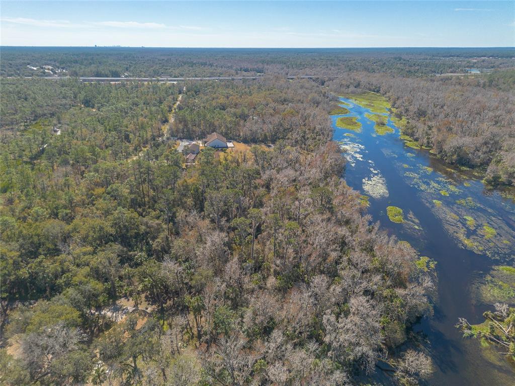 An aerial view shows a house nestled in a wooded area beside a river — 178 WEKIVA PARK DRIVE, SANFORD, FL