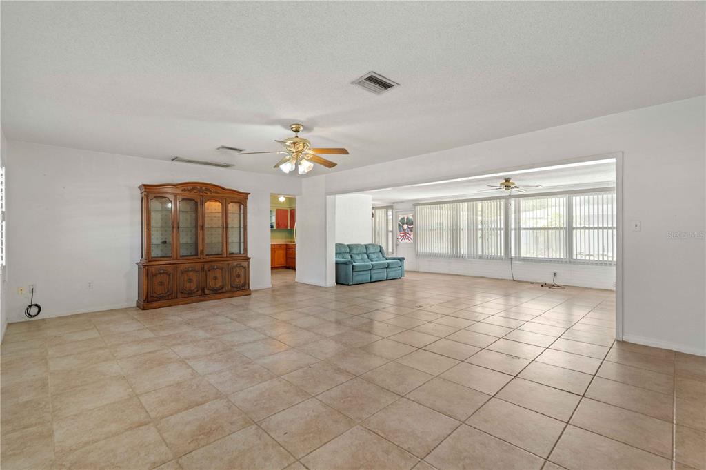 A spacious living room features light tile flooring, a large wooden hutch, and a sunroom — 927 PARKWOOD DRIVE, DUNEDIN, FL