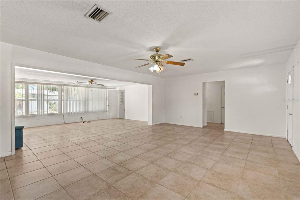 A spacious living area features beige tile flooring, white walls, and two ceiling fans — 927 PARKWOOD DRIVE, DUNEDIN, FL