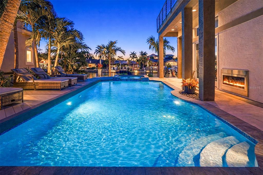 A swimming pool with a hot tub sits on a patio beside a modern house — 4635 DOLPHIN CAY LANE S, ST PETERSBURG, FL