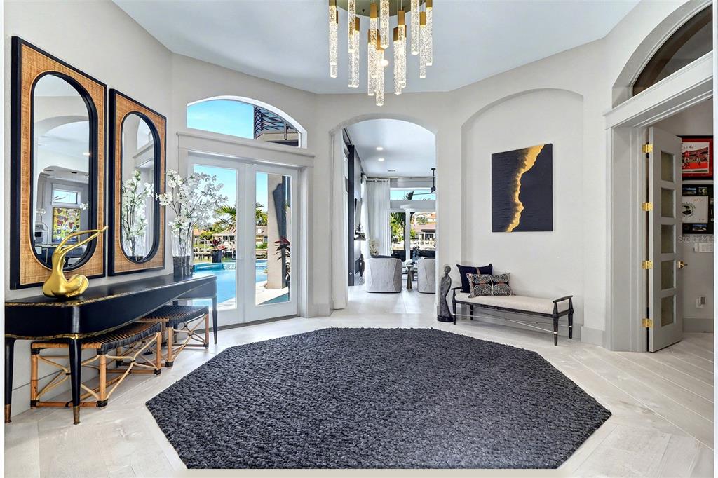 A bright foyer features a dark hexagonal rug, a chandelier, and views of a pool — 4635 DOLPHIN CAY LANE S, ST PETERSBURG, FL