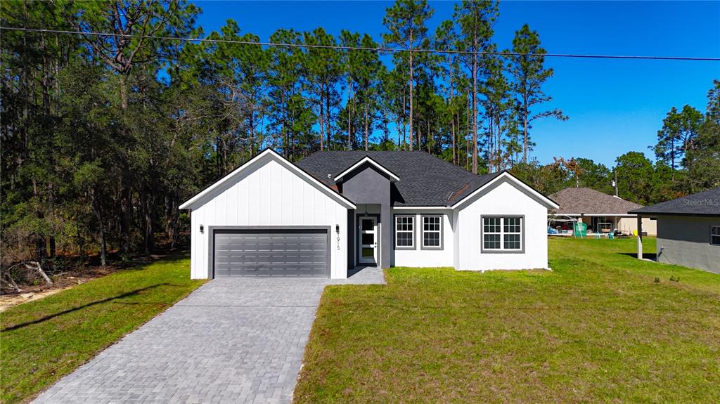 A modern single-story house with white siding, a dark gray garage, and a paved driveway — 1915 W LINDEN DRIVE, DUNNELLON, FL