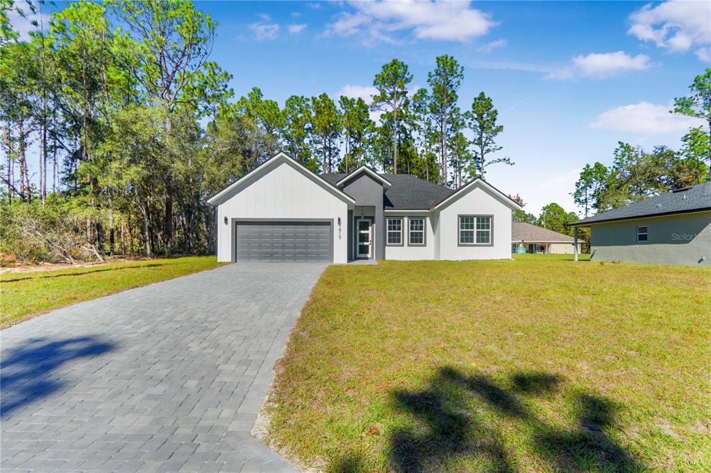 A single-story house with a white facade, gray garage, and a paved driveway — 1915 W LINDEN DRIVE, DUNNELLON, FL
