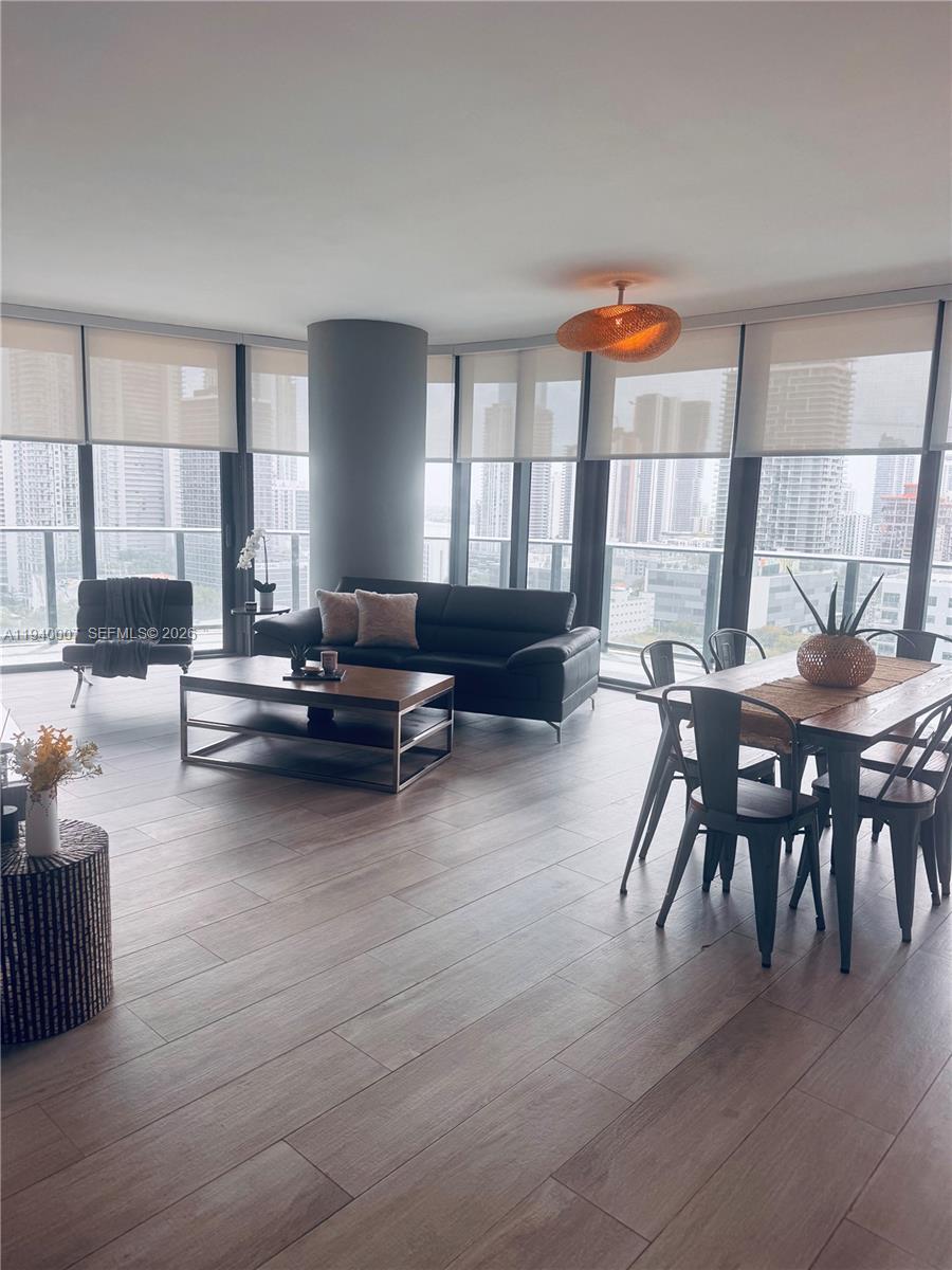 A modern living and dining area features floor-to-ceiling windows with city views — 121 NE 34th St # 1904, Miami FL 33137, MIAMI, FL